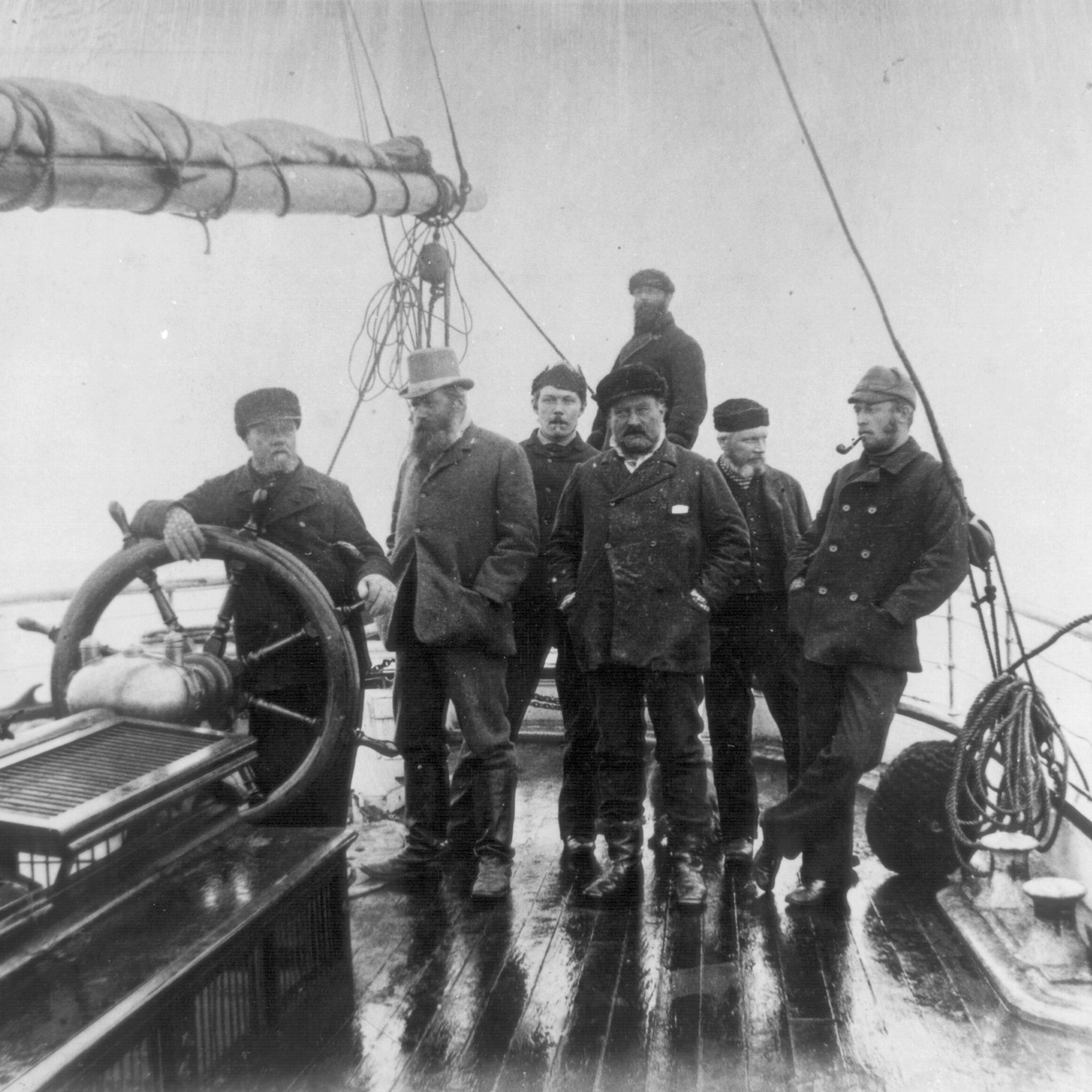 Group of men around the ship wheel of a boat