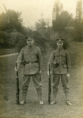 Conan Doyle standing with another man, both in military uniform with rifles at their side.